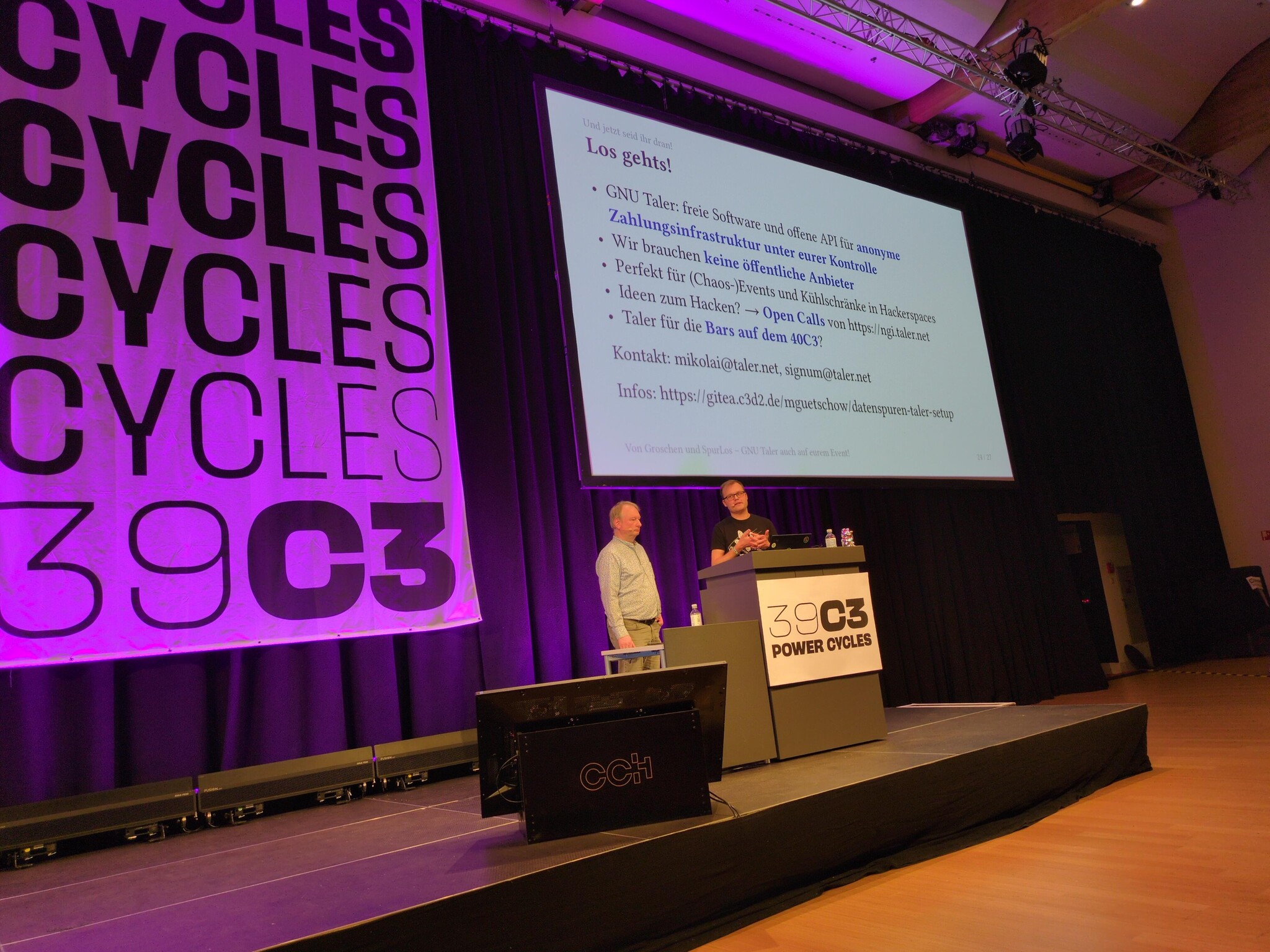 The presenters in front of the final slide at 39C3.